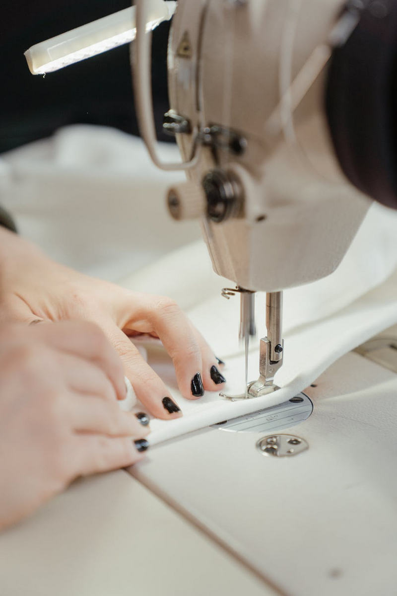 close up on women using sewing machine on fabrics
