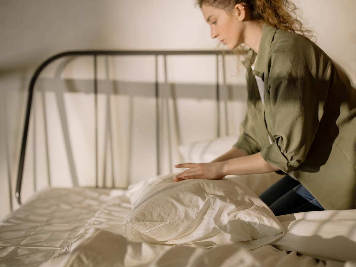 women removing bed sheets from foam mattress
