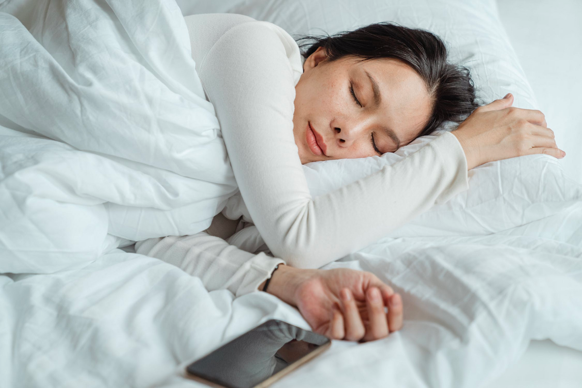 brunette women with white long-sleeve sleeping on bed