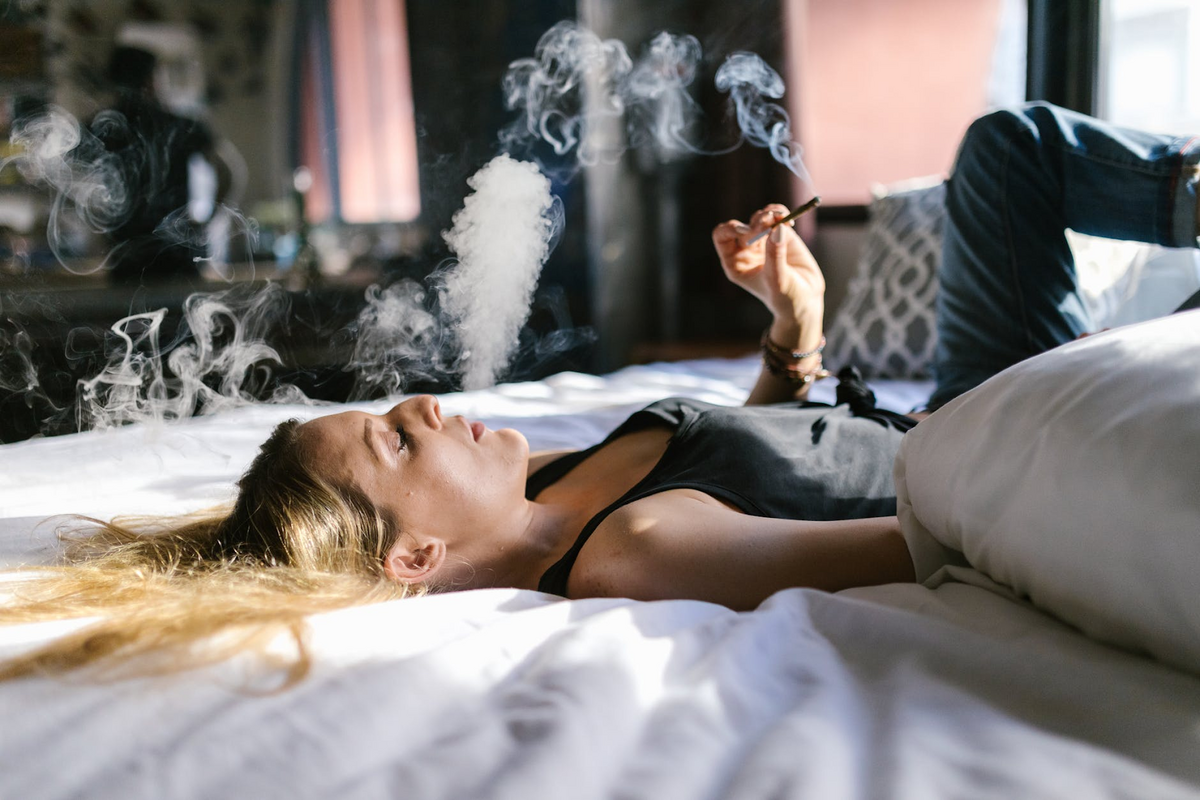 woman puffing cigarette on mattress