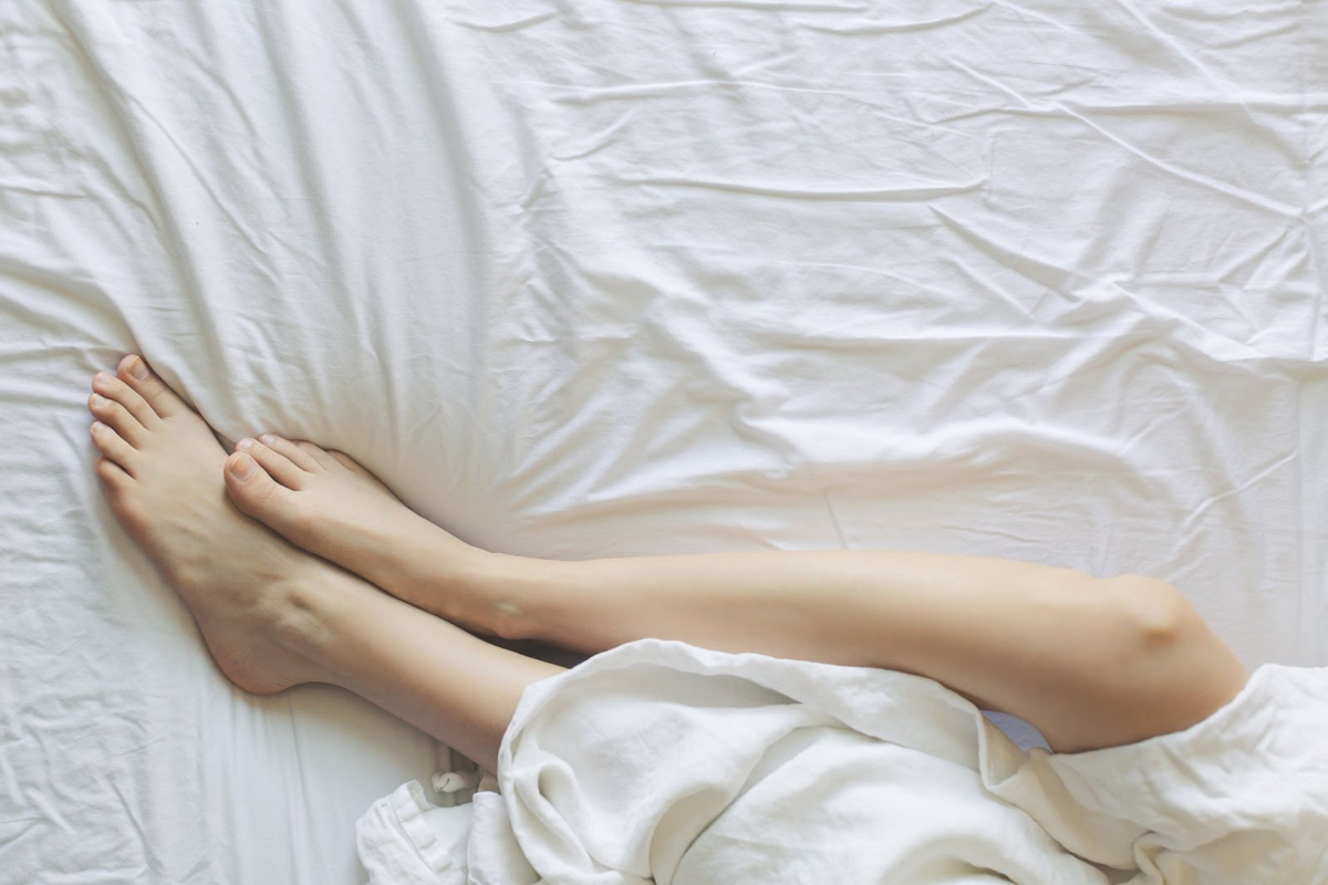 womans leg on a bed with white sheets
