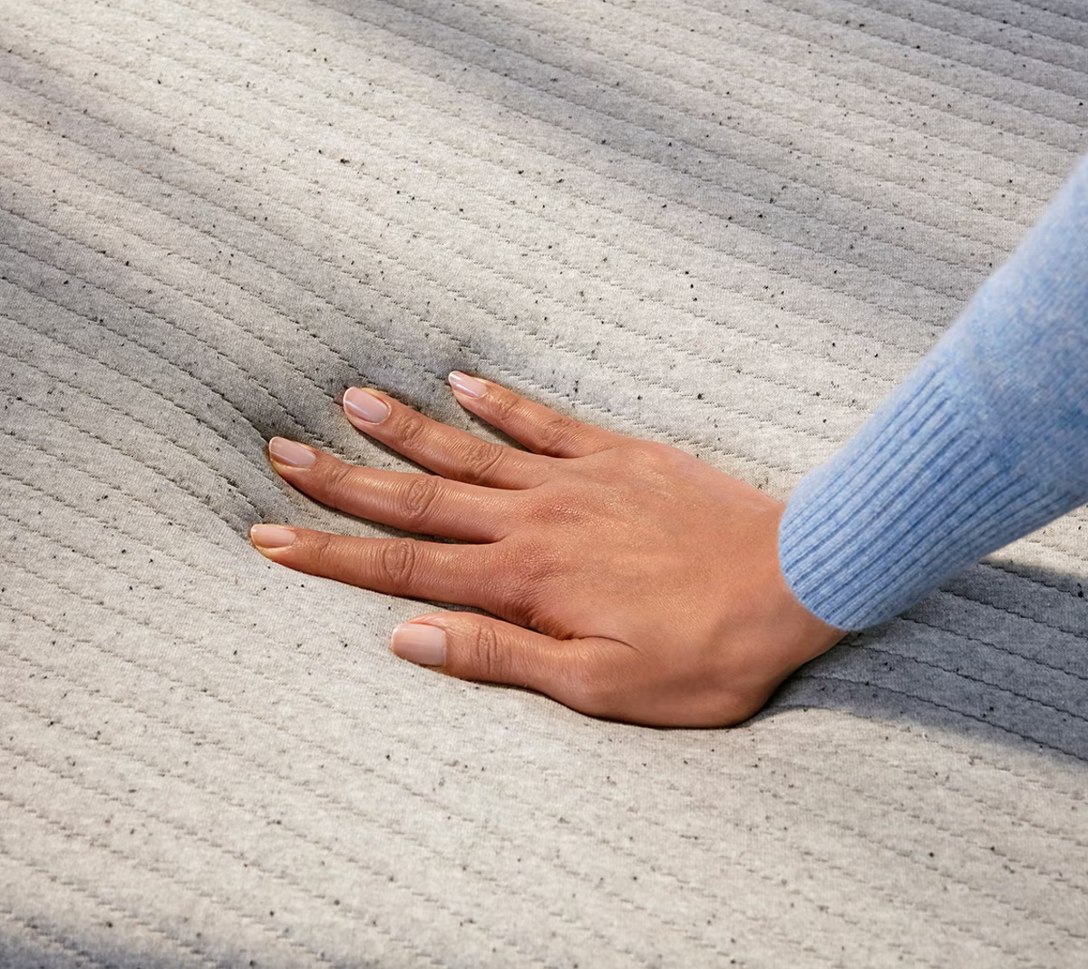 a hand pressing a foam mattress